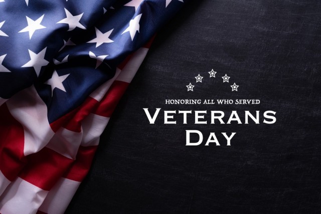Honoring All Who Served: Veterans Day text on blue background with a United States flag in the corner